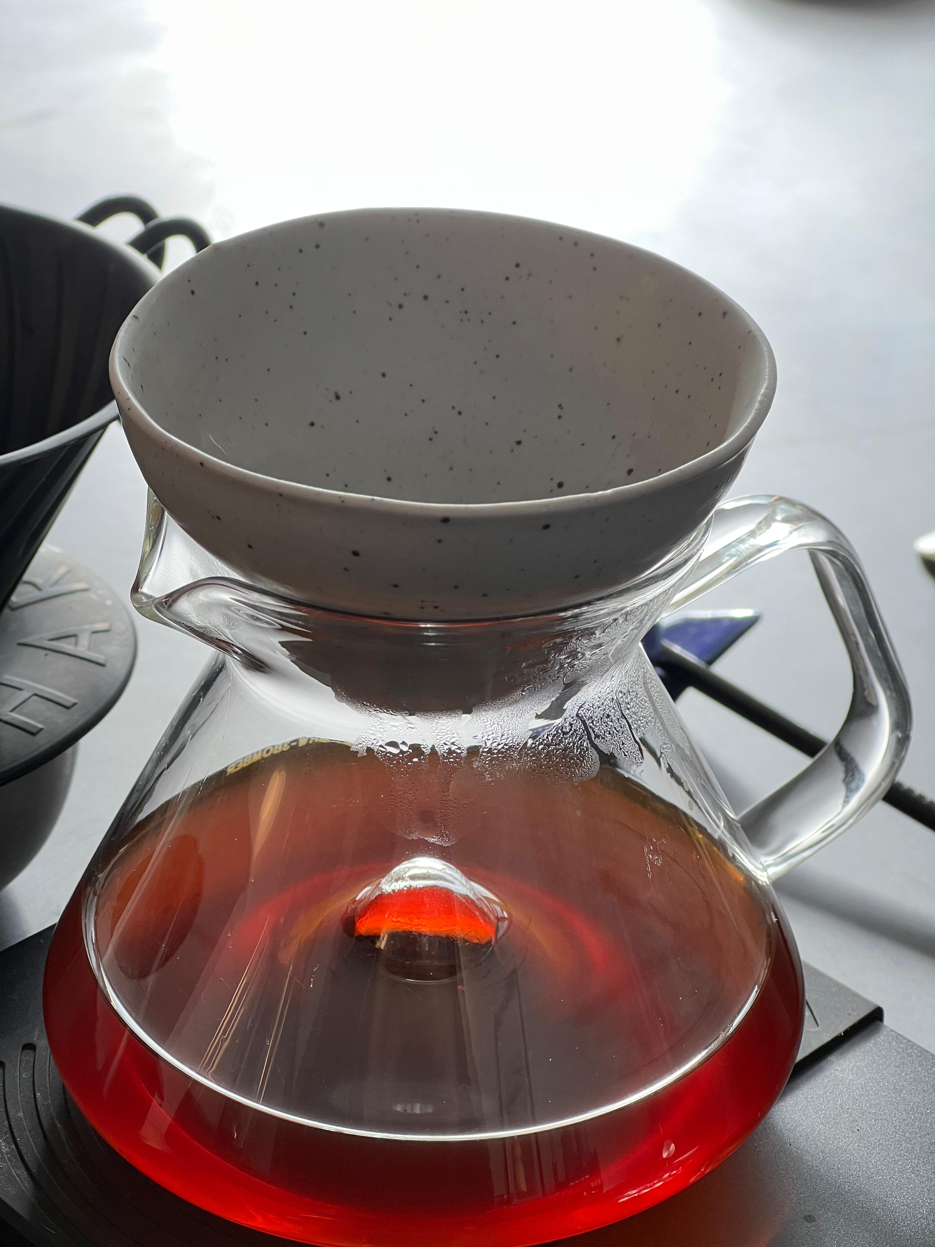 Coffee brewing setup with a glass carafe and filter on a stove.